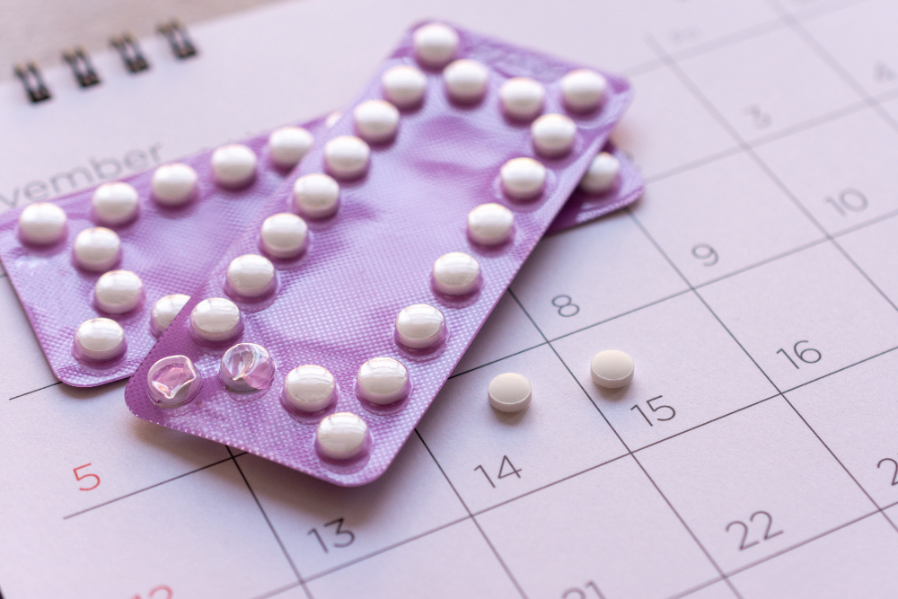 Cartelas de anticoncepcional com comprimidos sobre calendário mensal, indicando acompanhamento do ciclo e uso contínuo da medicação.